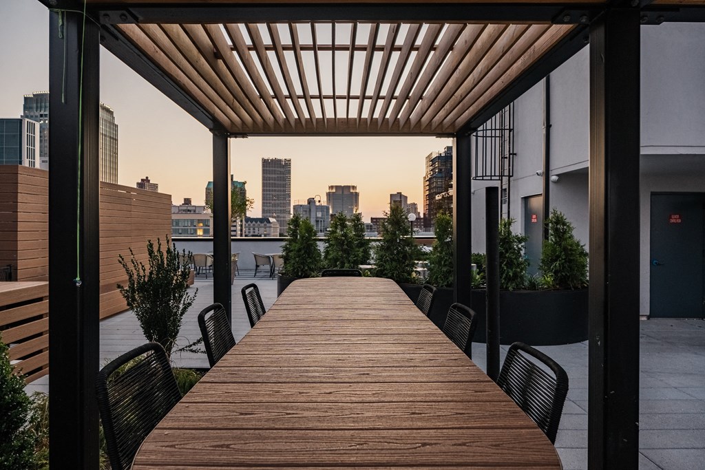a long wooden table on a balcony with a view of the city